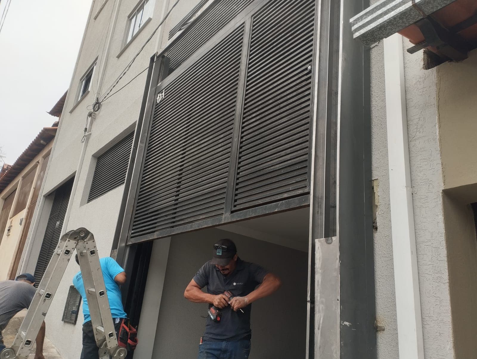 Equipe executando fabricação e instalação de portão sob medida em prédio residencial